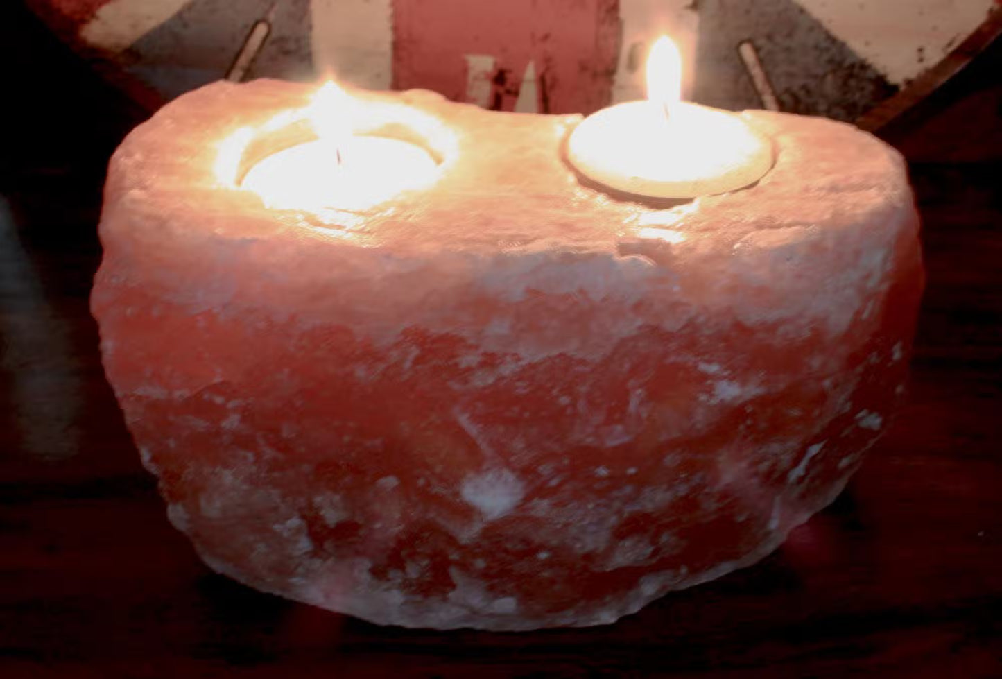 Two lit candles inside a textured pink stone container.