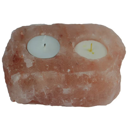 Rectangular pink salt block with two small candles inside on a white background
