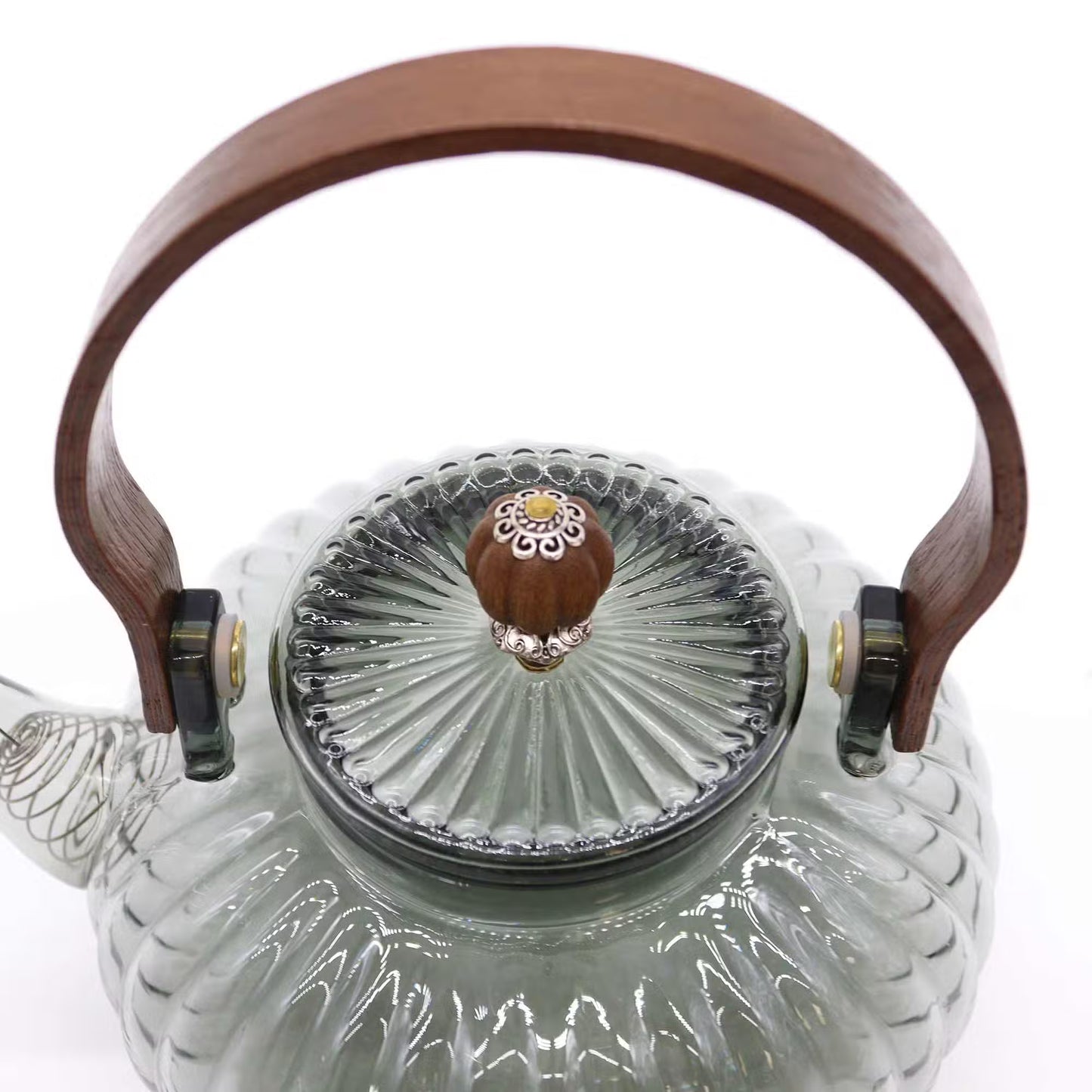 Glass teapot with wooden handle and decorative lid on a white background