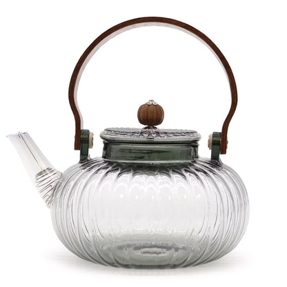 Clear glass teapot with wooden handle and lid knob on a white background