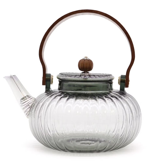 Clear glass teapot with wooden handle and lid knob on a white background