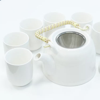 White ceramic teapot with metal mesh lid and six matching cups on a white background
