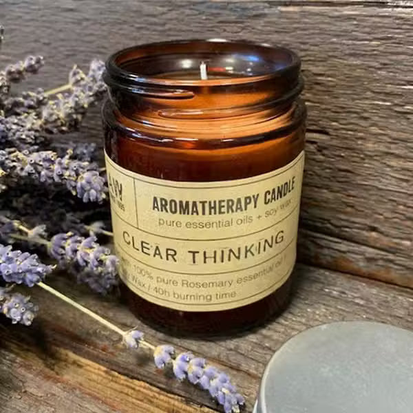 Aromatherapy candle labeled 'Clear Thinking' with lavender on a wooden surface