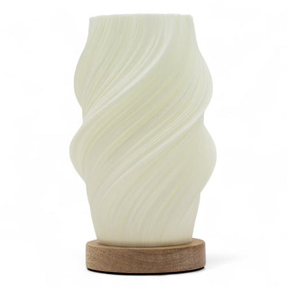 A sculptural table lamp with a wavy, ribbed translucent shade in an off-white finish, resting on a round natural wood base against a solid white background.