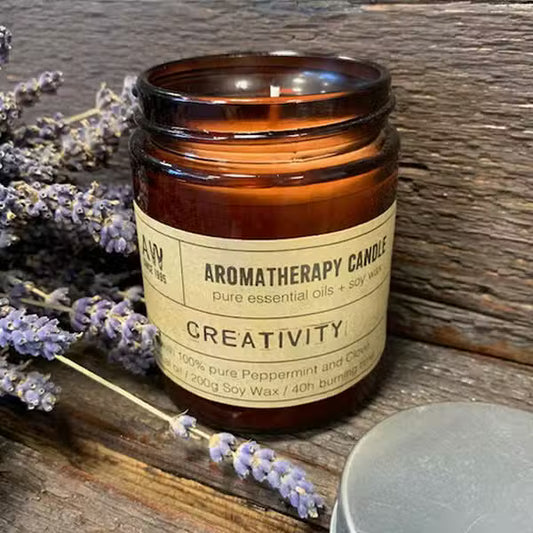 Aromatherapy candle labeled 'Creativity' with lavender flowers on a wooden surface