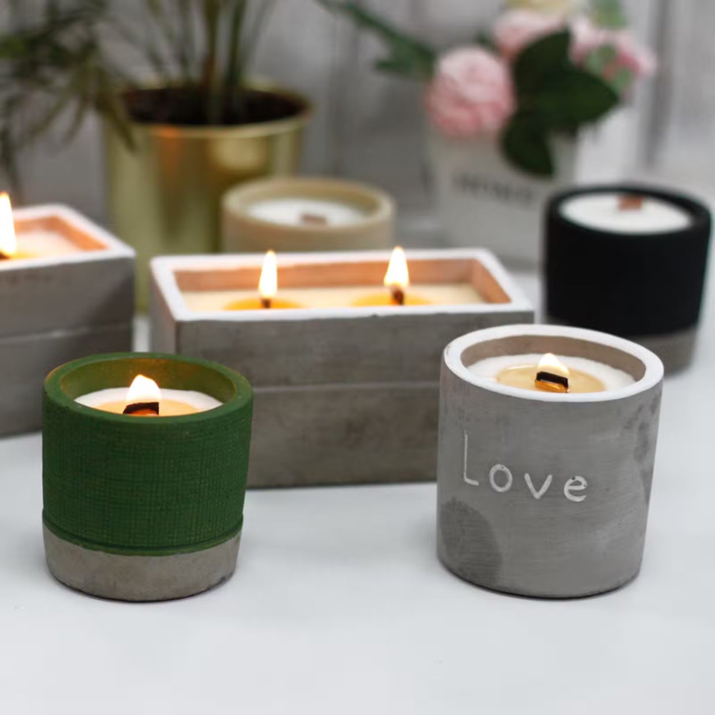 Candle holders with candles on a light surface, including a green holder and one labeled 'love'.