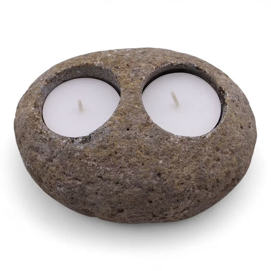 Rustic stone candle holder with two white candles on a white background