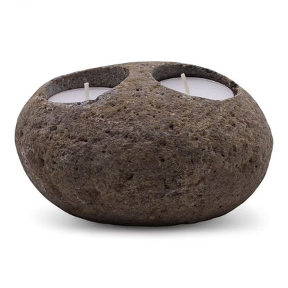 Rustic stone candle holder with two lit candles on a white background