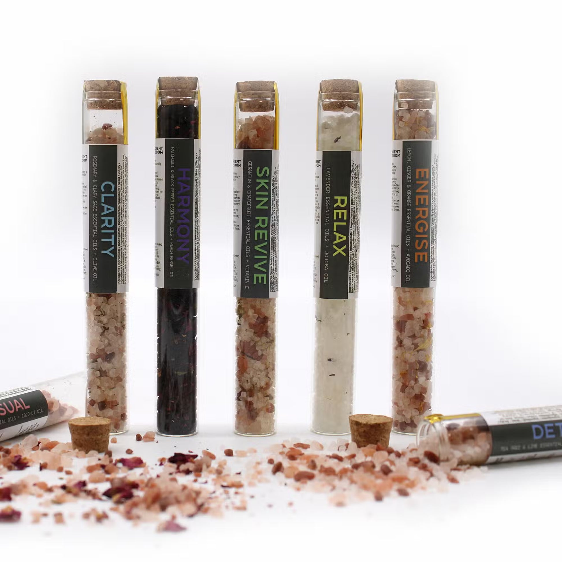 Five glass tubes with labels on a white background, containing different types of salt or spice mixtures.