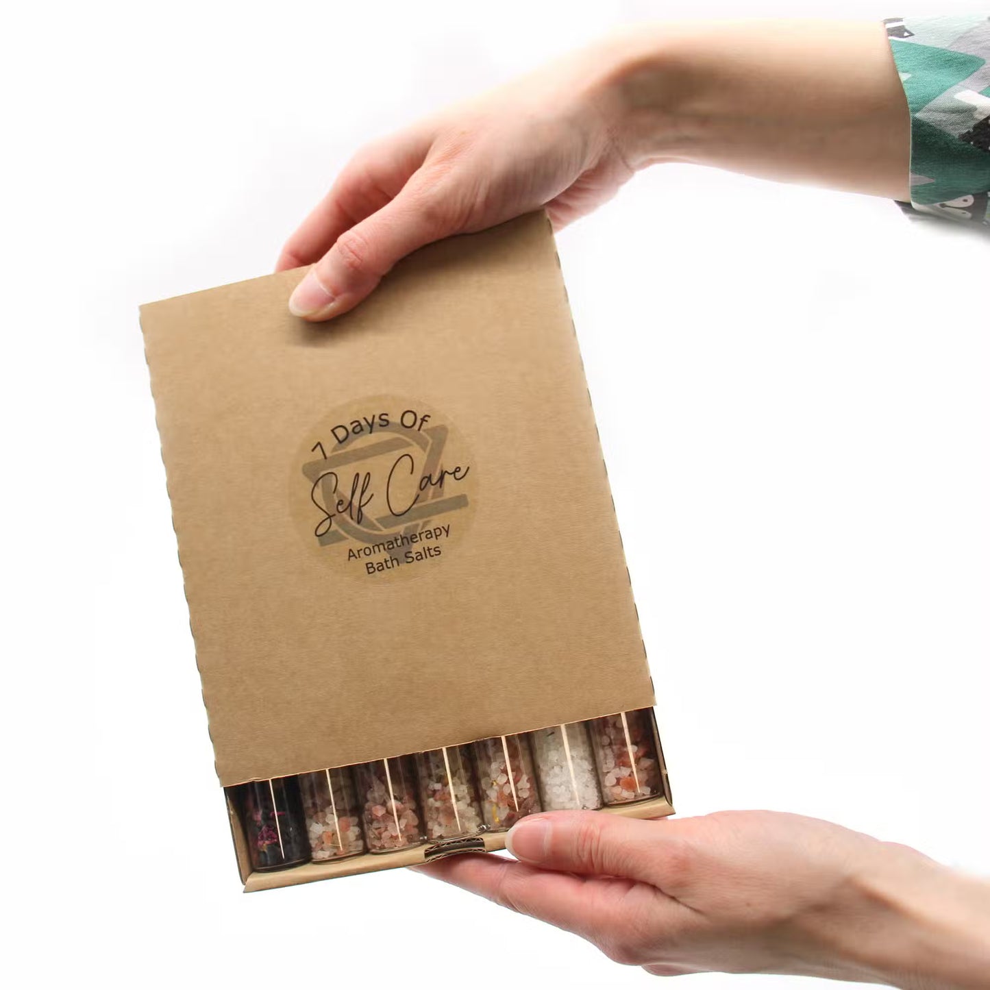Kraft paper box with '7 Days of Self Care' and 'Aromatherapy Bath Salts' text, held by a person.