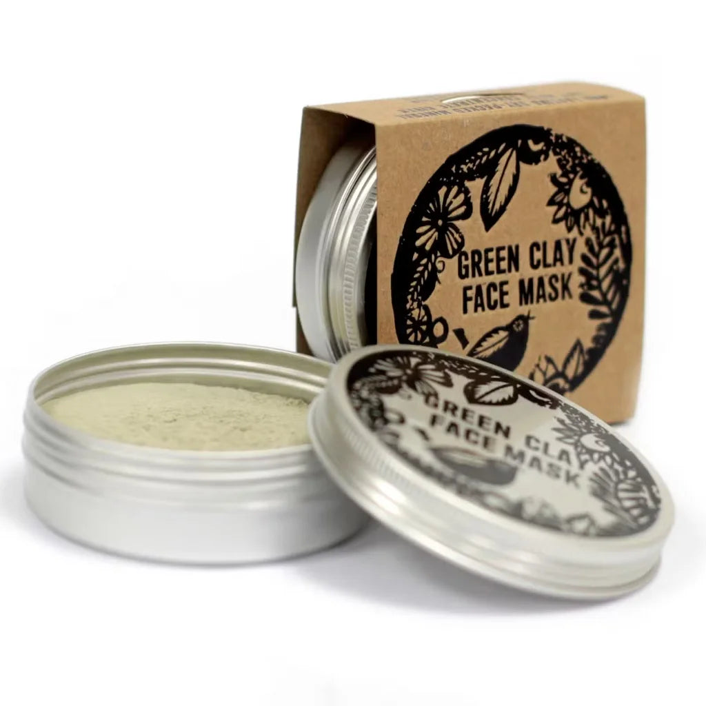 Green clay face mask in a metal tin with a cardboard box on a white background