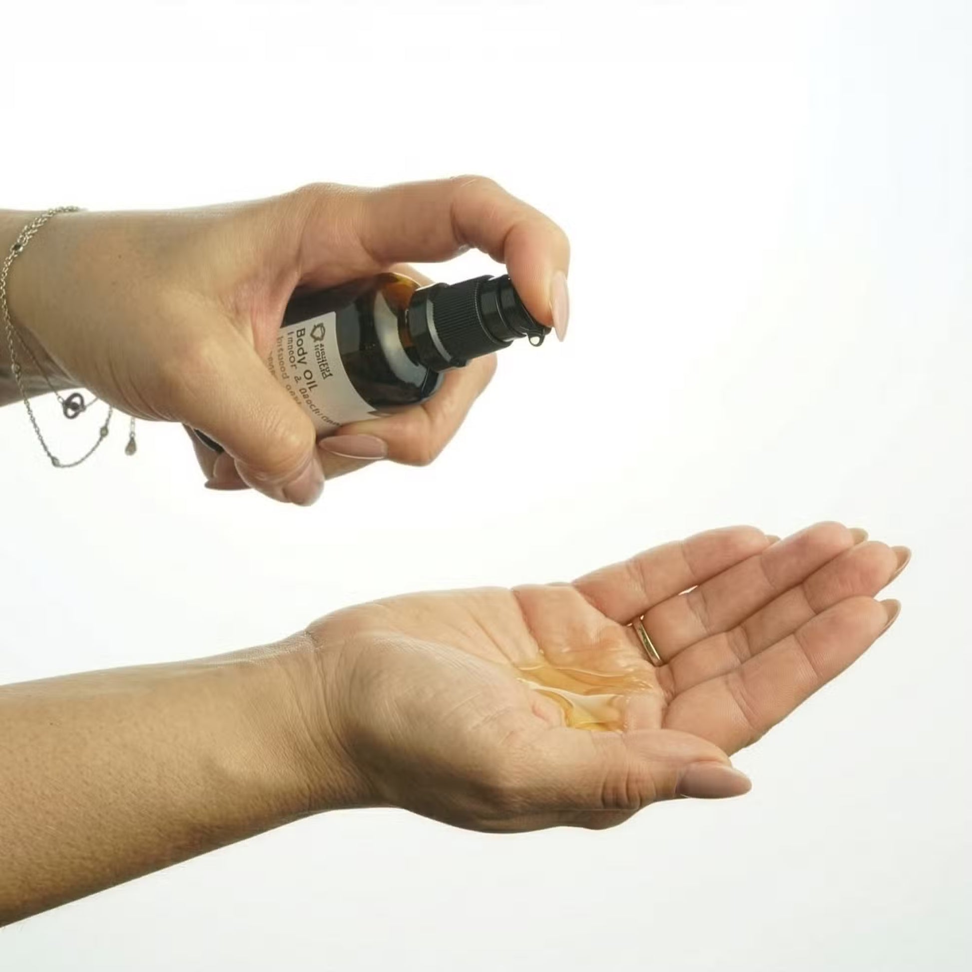 Hand holding a small bottle over another hand with a white background