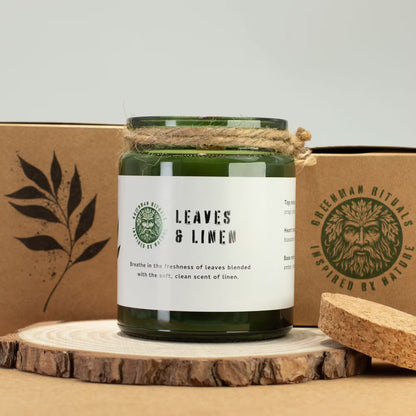 Green candle labeled 'Leaves & Linen' with a cardboard box featuring a logo in the background.
