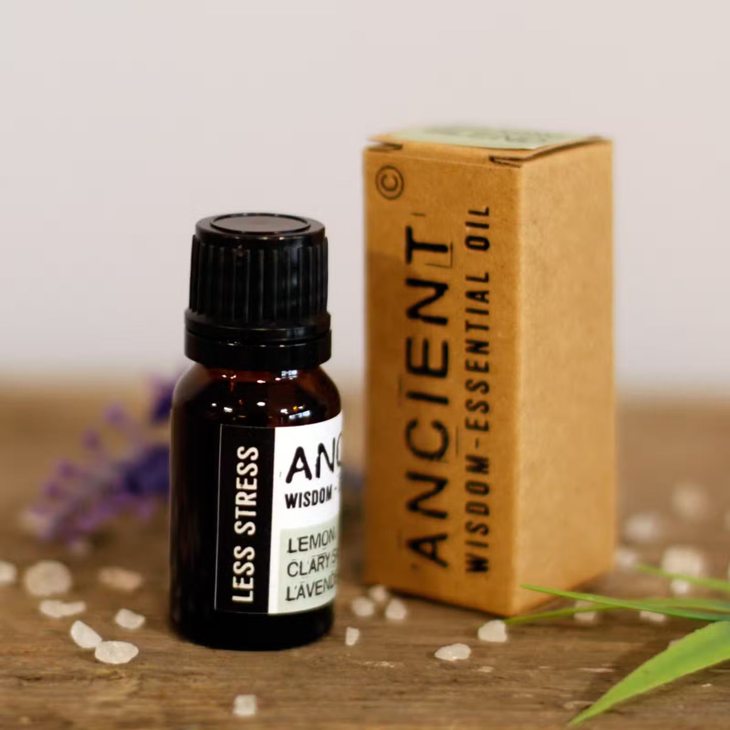 Bottle of Ancient Wisdom essential oil with packaging on a wooden surface