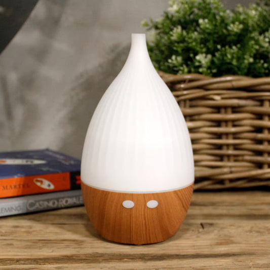 White and wooden diffuser on a wooden surface with books and plants in the background
