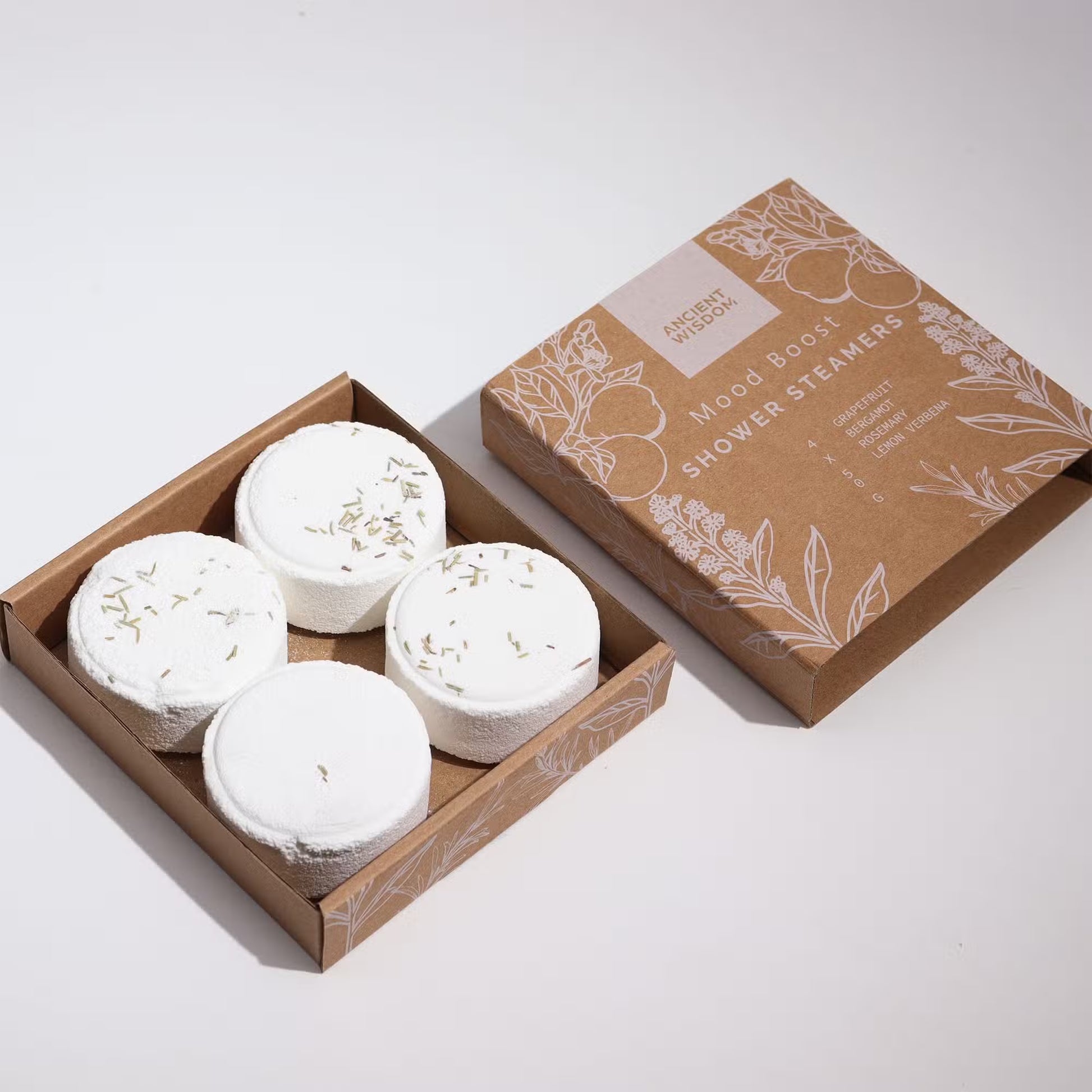 Four white bath bombs in a cardboard box with a decorative brown box on a light gray background