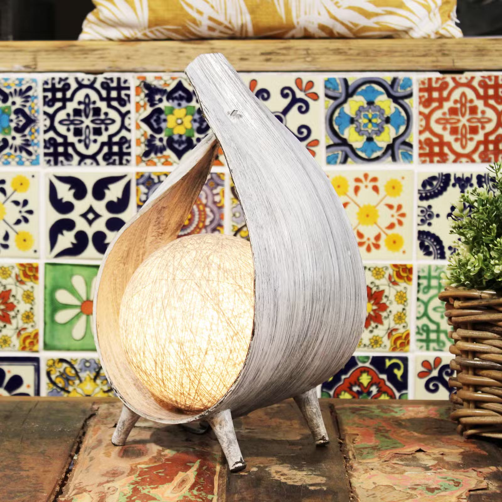 Decorative lamp with a unique design on a table against a colorful tiled wall.