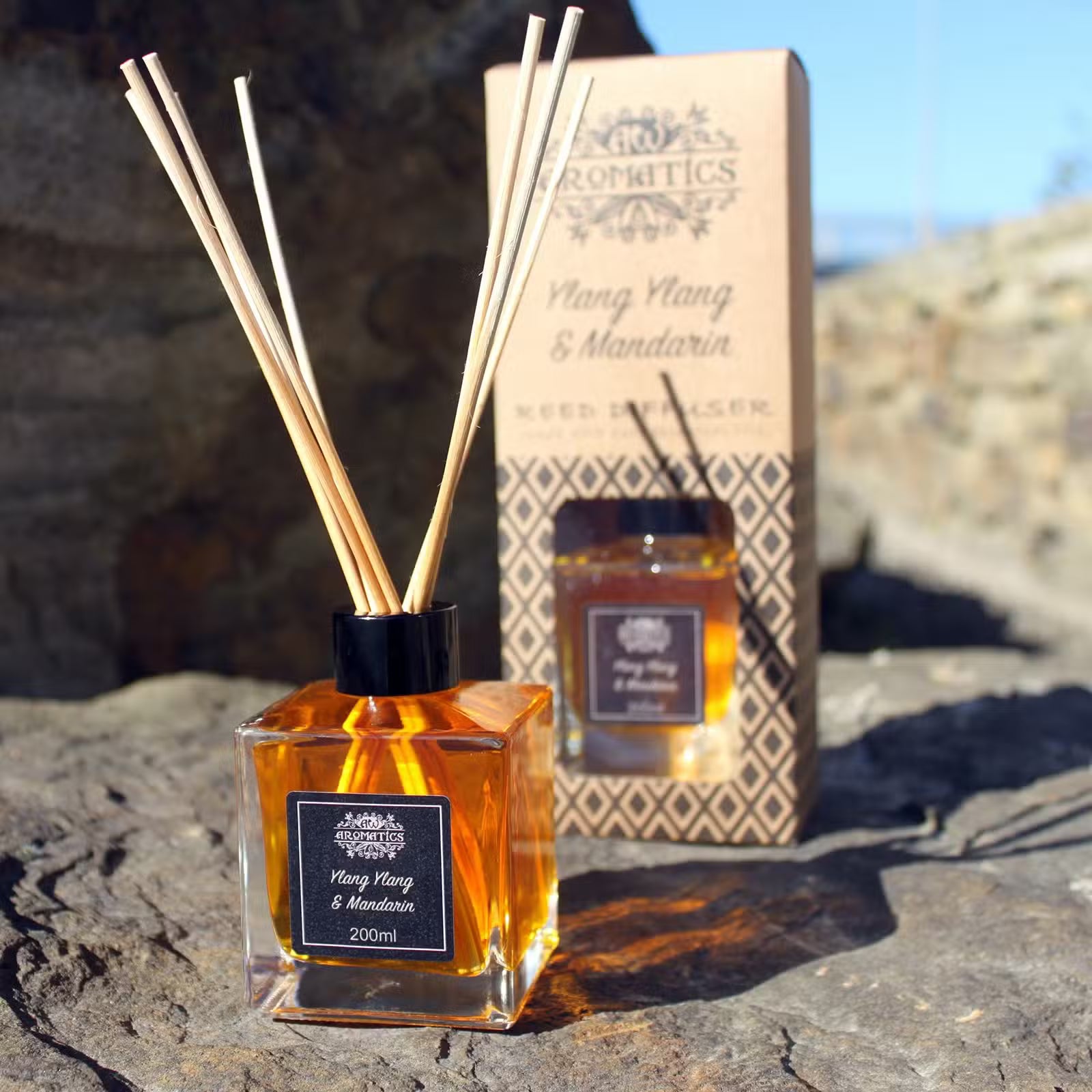 Aromatics diffuser with reeds and packaging on a stone surface