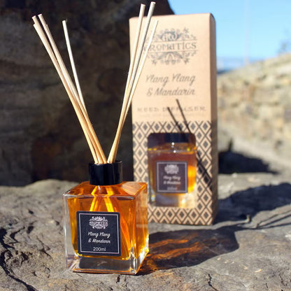 Aromatics diffuser with reeds and packaging on a stone surface