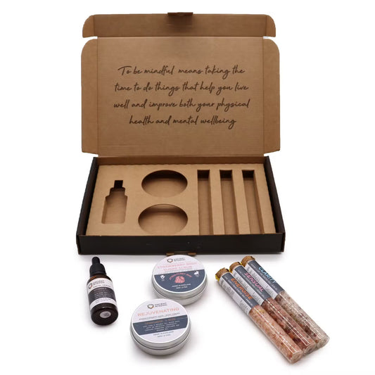 Open cardboard box with wellness products including tins and a dropper bottle on a white background.