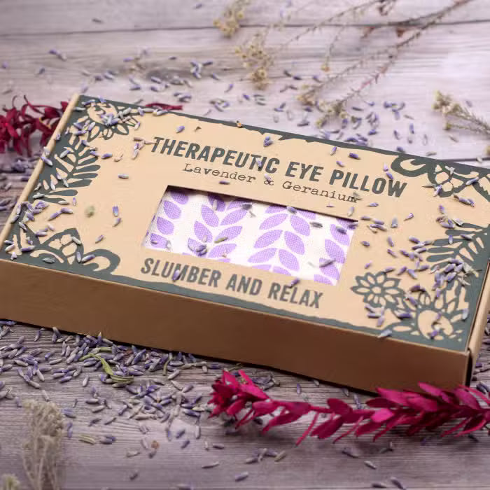 Therapeutic eye pillow packaging with lavender and geranium on a wooden surface.