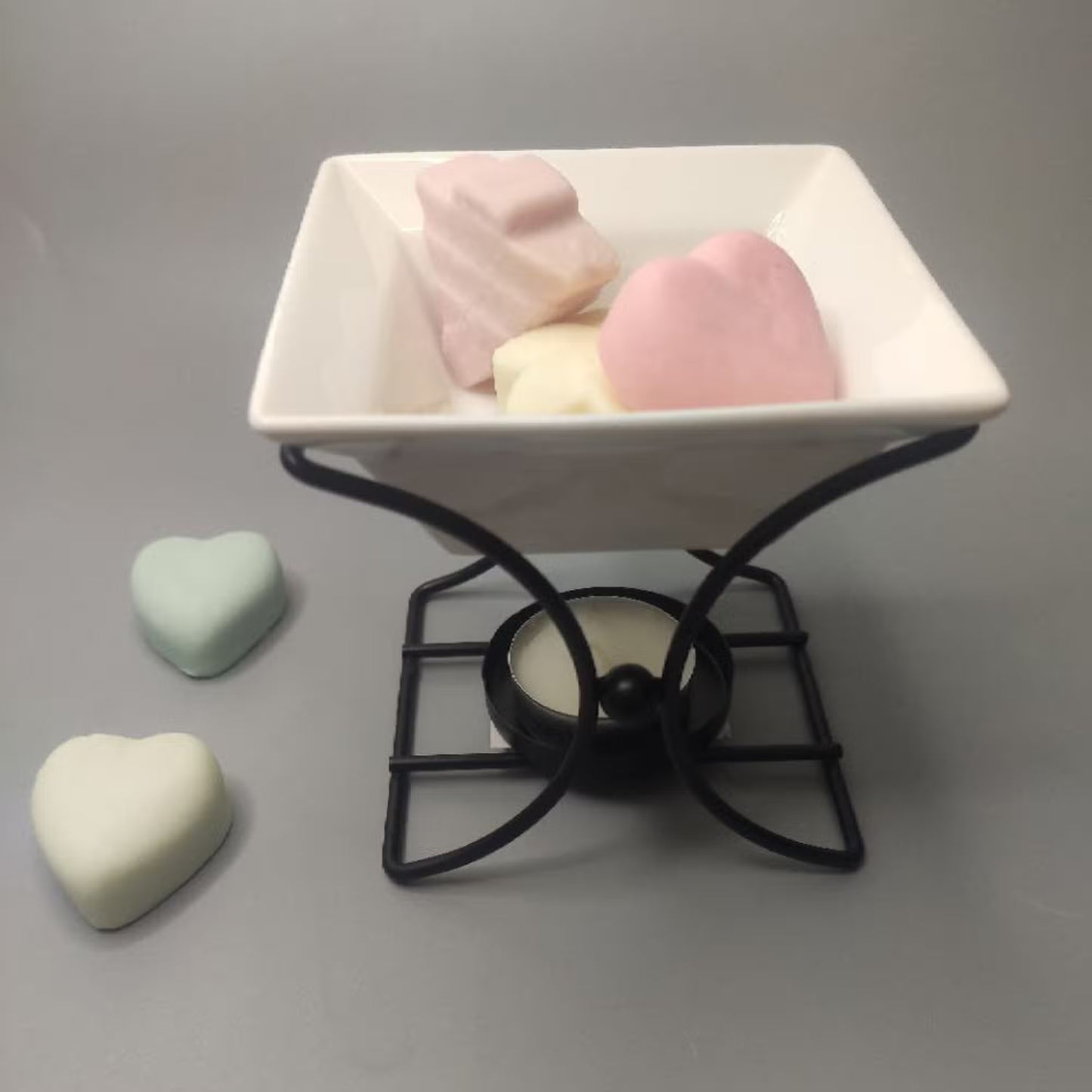 White ceramic dish with pink and green heart-shaped objects on a gray background