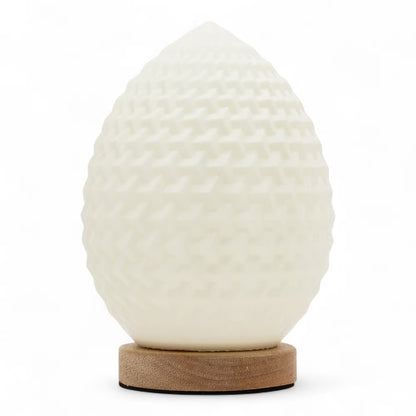 A sculptural egg-shaped lamp with a textured, dimpled off-white surface, resting on a round natural wood base against a clean white background.