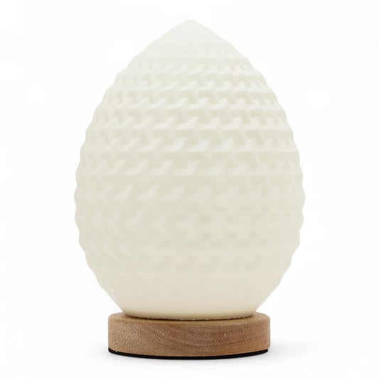 A sculptural egg-shaped lamp with a textured, dimpled off-white surface, resting on a round natural wood base against a clean white background.