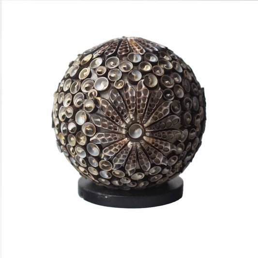 Decorative spherical object with shell-like material on a white background