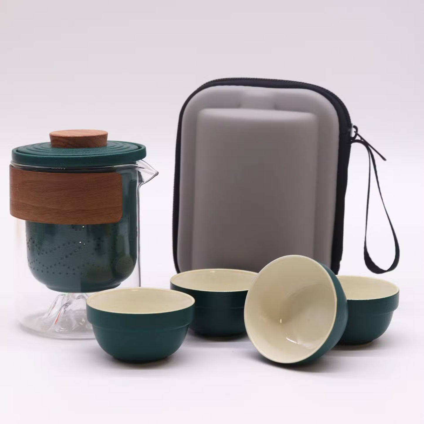 Tea set with green teapot and bowls, gray carrying case on a white background