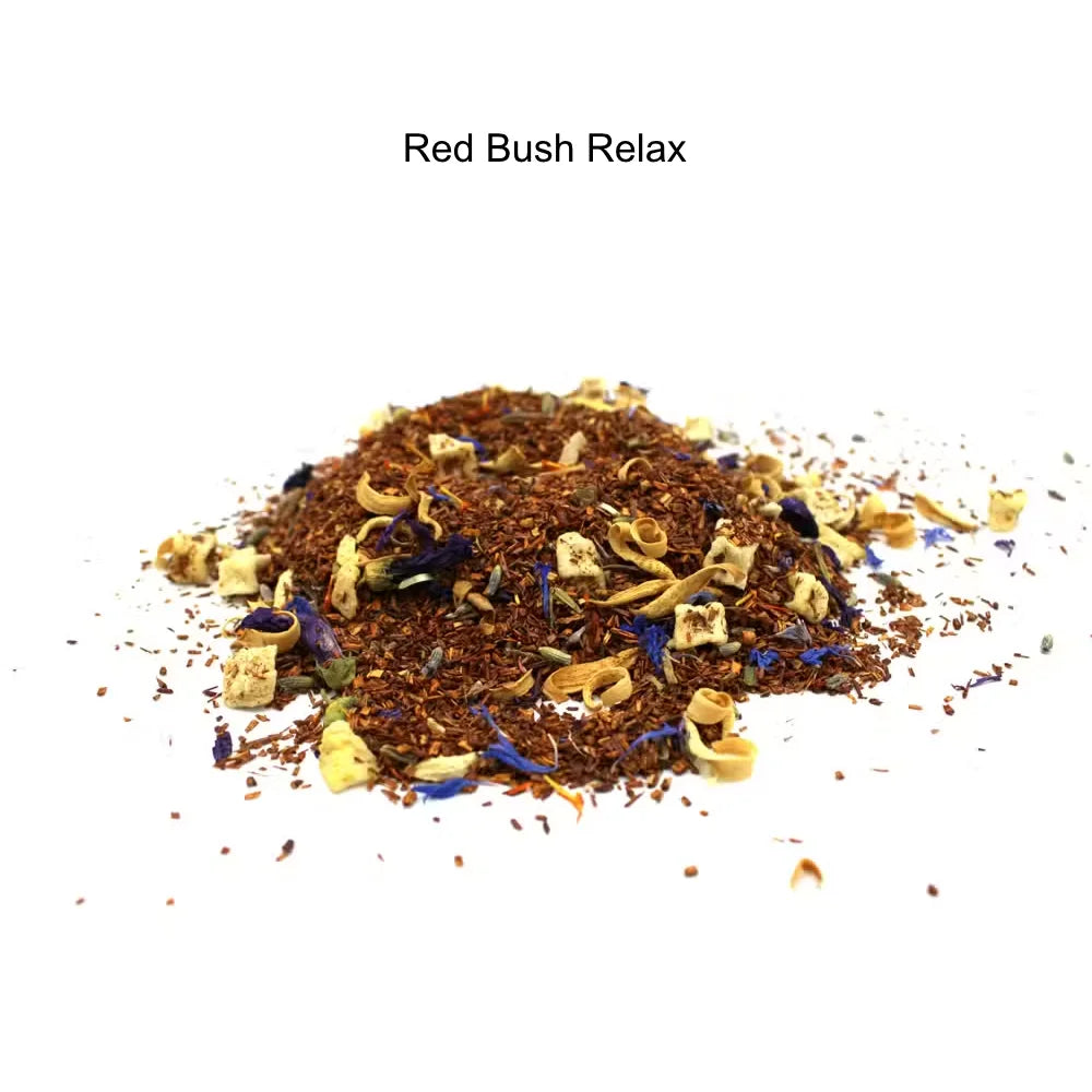 A small pile of loose-leaf herbal tea labeled 'Red Bush Relax' on a plain white background. The tea blend is predominantly reddish-brown with scattered pale yellow dried flower pieces and a few blue accents.