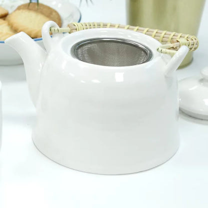 White ceramic teapot with a metal mesh filter on a white surface.
